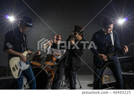 Musician band hand holding the microphone and singing a song and playing music instrument with Fellow band musicians on black background with spot light and lens flare, musical concept Musician band hand holding the microphone and singing a song and playing music instrument with Fellow band musicians on black background with spot light and lens flare, musical concept 40493225