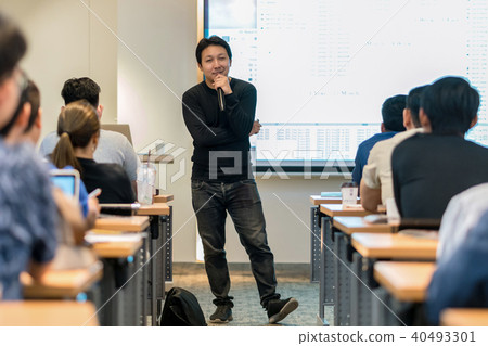 Asian Speaker with casual suit on the stage in low light over the presentation screen in the business or education seminar Asian Speaker with casual suit on the stage in low light over the presentation screen in the business or education seminar 40493301