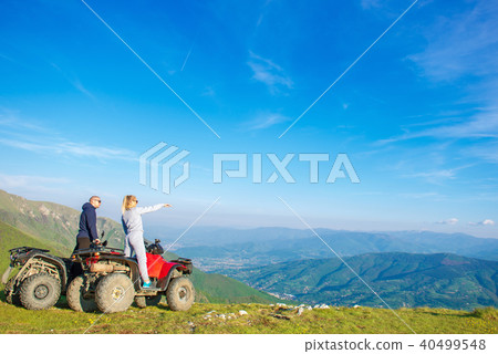 Beautiful couple is watching the sunset from the mountain sitting on atv quadbike 40499548