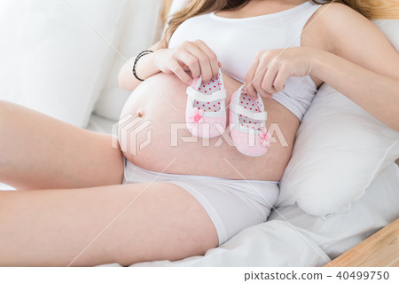 pregnant woman holding baby shoes pregnant woman holding baby shoes 40499750