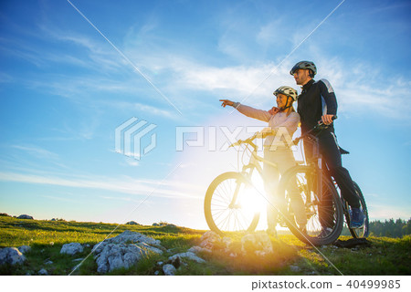 Biker couple with mountain bike pointing in distance at countryside 40499985
