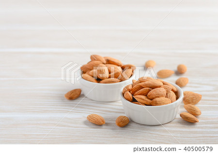 Almonds in a bowls on a white wooden background. Almonds in a bowls on a white wooden background. 40500579