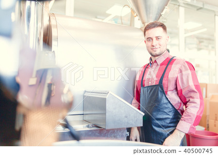 Photo of brunette businessman in apron standing next to industrial roster Photo of brunette businessman in apron standing next to industrial roster 40500745