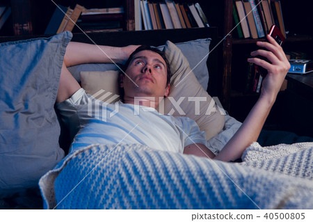 Picture of man with sleeplessness with phone in hands lying in bed Picture of man with sleeplessness with phone in hands lying in bed 40500805