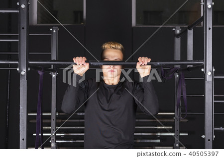 Strong young fit man doing pull-ups on a bar in a gym 40505397