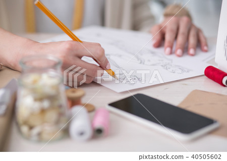 Young female couturier sketching new garment 40505602