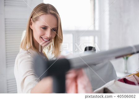 Reflective optimistic businesswoman examining garments Reflective optimistic businesswoman examining garments 40506002
