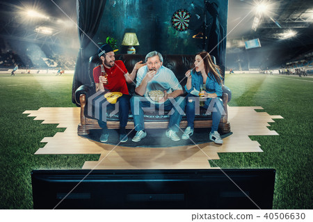 Ardent fans are sitting on the sofa and watching TV in the middle of a football field. Ardent fans are sitting on the sofa and watching TV in the middle of a football field. 40506630