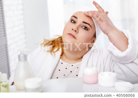 Serious fat woman taking care of her skin 40508008