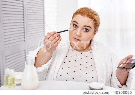 Determined stout woman applying make-up 40508090
