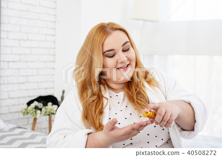 Content stout woman applying hair oil 40508272