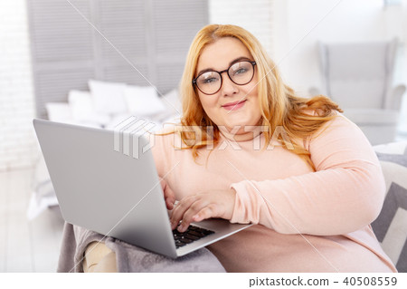 Smiling stout woman working on her laptop 40508559