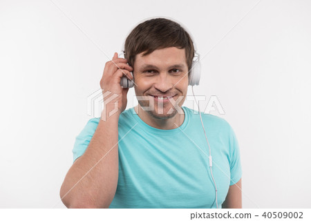 Cheerful positive man touching his headphones Cheerful positive man touching his headphones 40509002