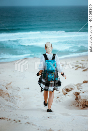 Woman hiker with backpack going down a sand dune towards the lonely beach. Sao Vicente Cape Verde Woman hiker with backpack going down a sand dune towards the lonely beach. Sao Vicente Cape Verde 40509569