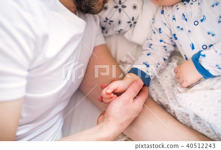 Father holding hand of a sleeping toddler boy in bed at home. Father holding hand of a sleeping toddler boy in bed at home. 40512243