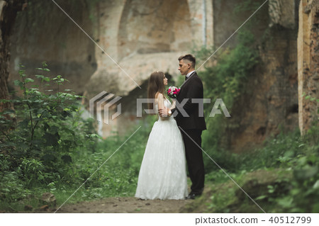 Beautiful fairytale newlywed couple hugging near old medieval castle Beautiful fairytale newlywed couple hugging near old medieval castle 40512799