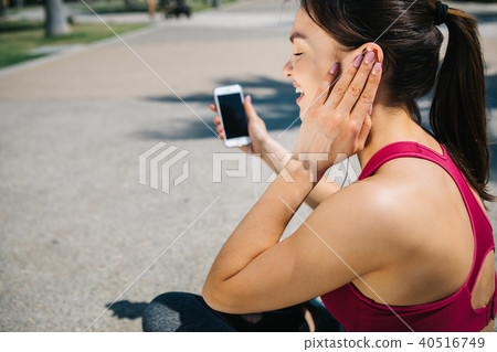 Excited female athlete listening to music after workout 40516749