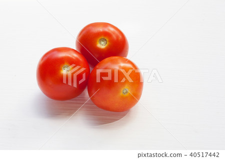 Three red tomatoes on a white . Three red tomatoes on a white . 40517442