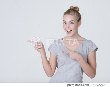 Smiling pretty woman pointing finger away Smiling pretty woman pointing finger away 40522639