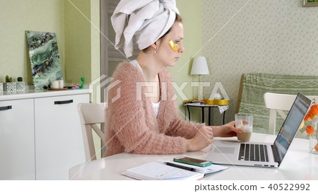 attractive business woman applying cosmetic facial spots at home, working behind laptop 40522992