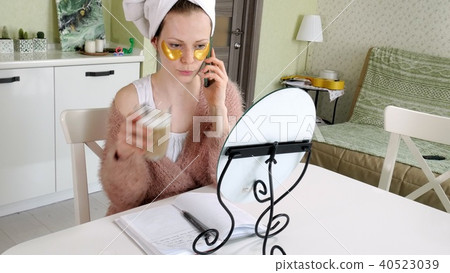 attractive business woman applying cosmetic facial spots at home, talking on the phone attractive business woman applying cosmetic facial spots at home, talking on the phone 40523039