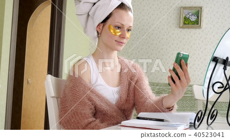 attractive business woman applying cosmetic facial spots at home, talking on the phone attractive business woman applying cosmetic facial spots at home, talking on the phone 40523041