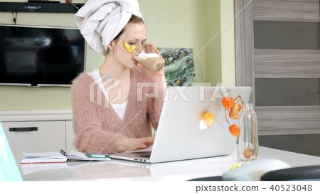 attractive business woman applying cosmetic facial spots at home, working behind laptop 40523048
