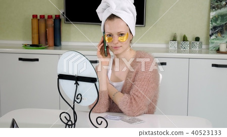 attractive business woman applying cosmetic facial spots at home, talking on the phone attractive business woman applying cosmetic facial spots at home, talking on the phone 40523133