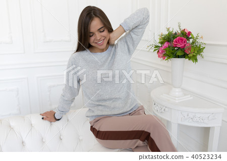 Beautiful woman in grey sweatshirt sitting on the couch. Mock-up. 40523234
