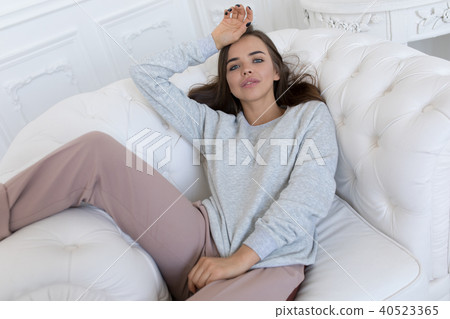 Beautiful smiling woman sitting on a white couch. 40523365