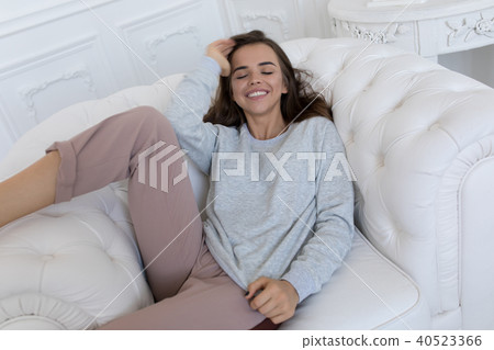 Beautiful smiling woman sitting on a white couch. 40523366
