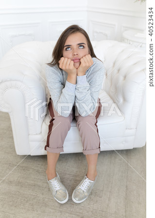 Beautiful pensive woman sitting on the couch. Beautiful pensive woman sitting on the couch. 40523434