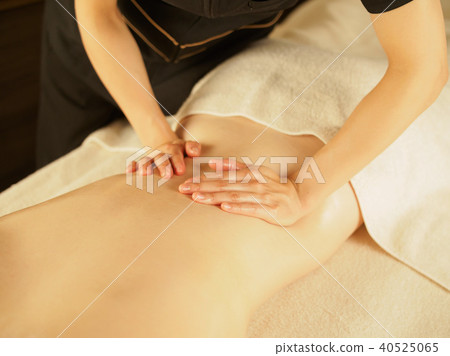 Woman draining waist fat and waste products in dimly lit beauty salon 40525065