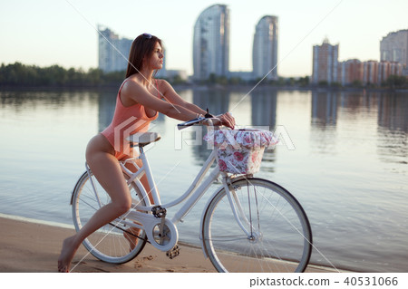 Portrait of a woman in a swimsuit on a bicycle on the river bank. 40531066