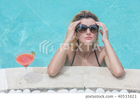 Woman in bikini with cocktail near pool Woman in bikini with cocktail near pool 40533821