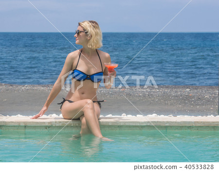 Woman in bikini with cocktail near pool 40533828