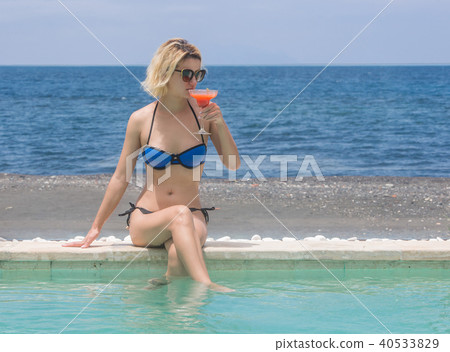 Woman in bikini with cocktail near pool 40533829