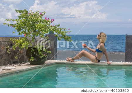 Woman in bikini with cocktail near pool Woman in bikini with cocktail near pool 40533830
