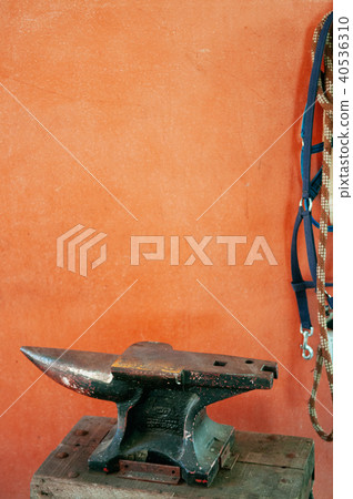 Old anvil on orange concrete wall, old tool. 40536310