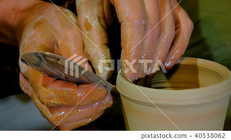 Professional potter shaping mug with special tool in pottery workshop 40538062