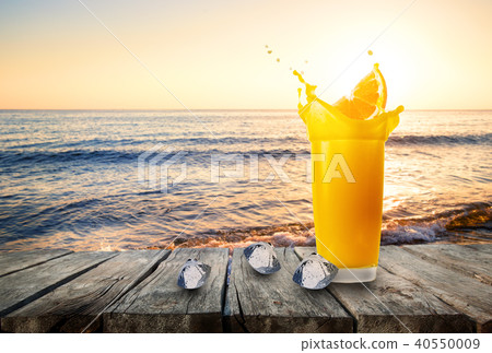 Glass of orange juice with splash from orange slice and ice 40550009
