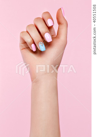 Beautiful pink and blue manicure with crystals on female hand. Close-up. 40551508