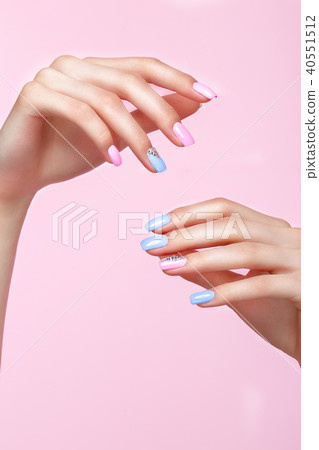 Beautiful pink and blue manicure with crystals on female hand. Close-up. 40551512