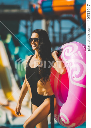 laughing woman with swim ring near pool and slides 40553947