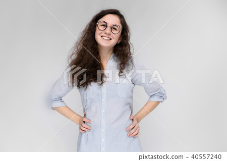Portrait of a happy young girl in glasses. Beautiful young girl on a gray background. A young girl 40557240