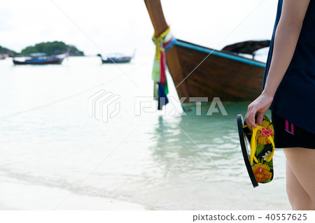 girl hold slipper walking on white sand relax time 40557625