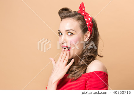 Beautiful young woman with pinup make-up and hairstyle. Studio shot on pastel background 40560716
