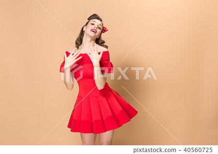 Beautiful young woman with pinup make-up and hairstyle. Studio shot on pastel background 40560725