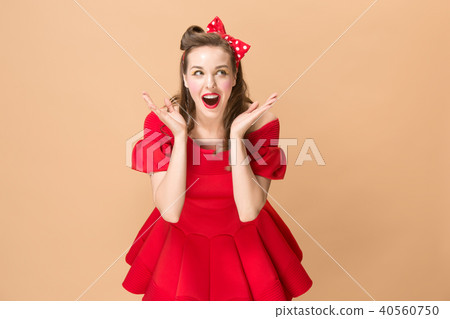 Beautiful young woman with pinup make-up and hairstyle. Studio shot on pastel background Beautiful young woman with pinup make-up and hairstyle. Studio shot on pastel background 40560750