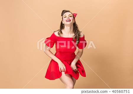 Beautiful young woman with pinup make-up and hairstyle. Studio shot on pastel background Beautiful young woman with pinup make-up and hairstyle. Studio shot on pastel background 40560751